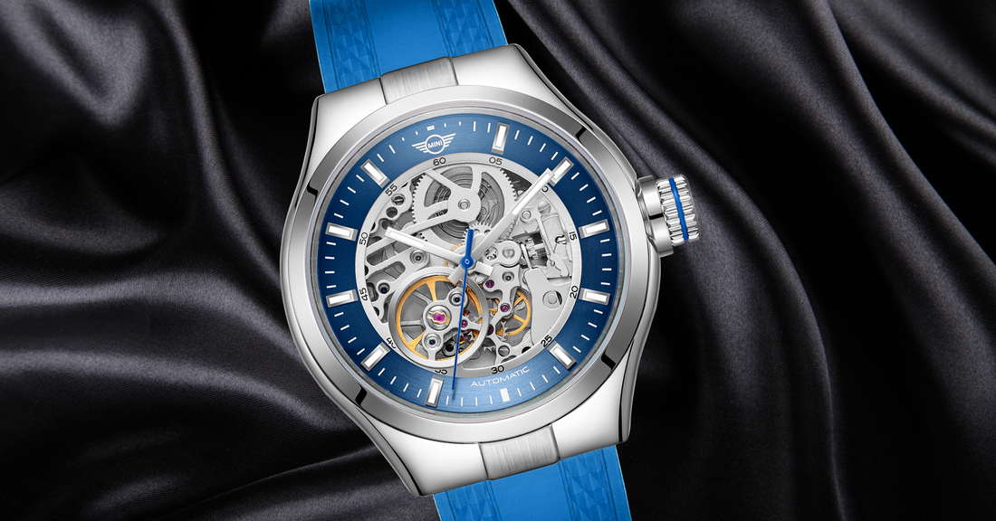 Stylish watches from MINI Cooper featuring a blue strap and skeleton dial with silver case on black satin background