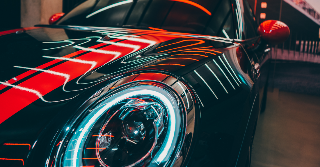 Close-up of a sleek black MINI Cooper with illuminated headlights showcasing bold design and style