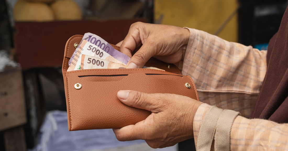 Person holding a brown wallet with cash inside representing Budget-Friendly Watches of 2025 affordability