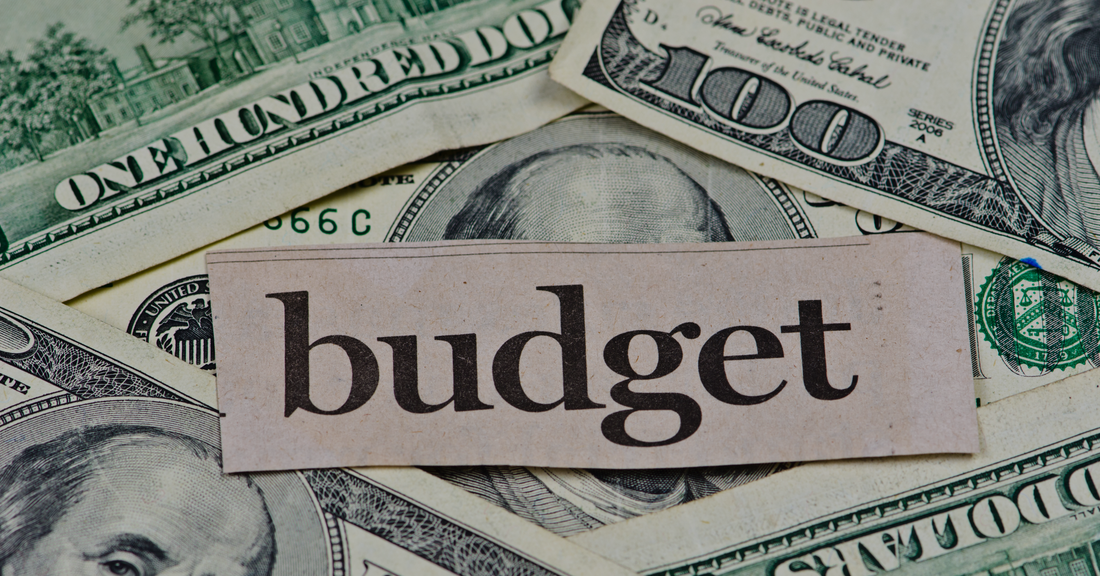 Budget-Friendly Watches concept with the word budget on paper over US hundred dollar bills