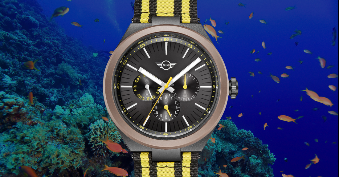 Close-up of a black and yellow MINI Cooper Watches with a sporty strap against an underwater coral reef background